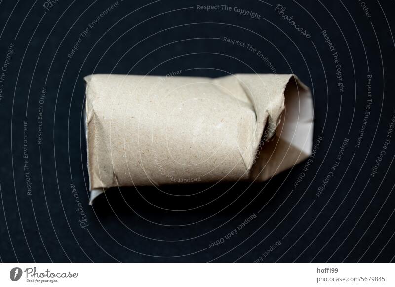 Close-up of an empty, dented toilet roll against a black background Toilet paper roll crumpled demolished Empty Coil paperboard Paper role used toilet paper