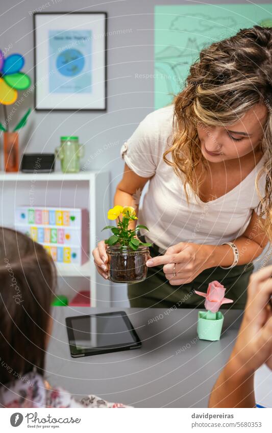 Female teacher showing pansy plant roots to her students in ecology classroom woman female pointing botanical botany flower portrait nature natural