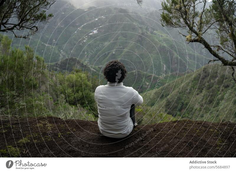 Unrecognizable curly haired woman admiring mountains traveler admire nature highland ridge environment trip summer female hands crossed tree countryside green