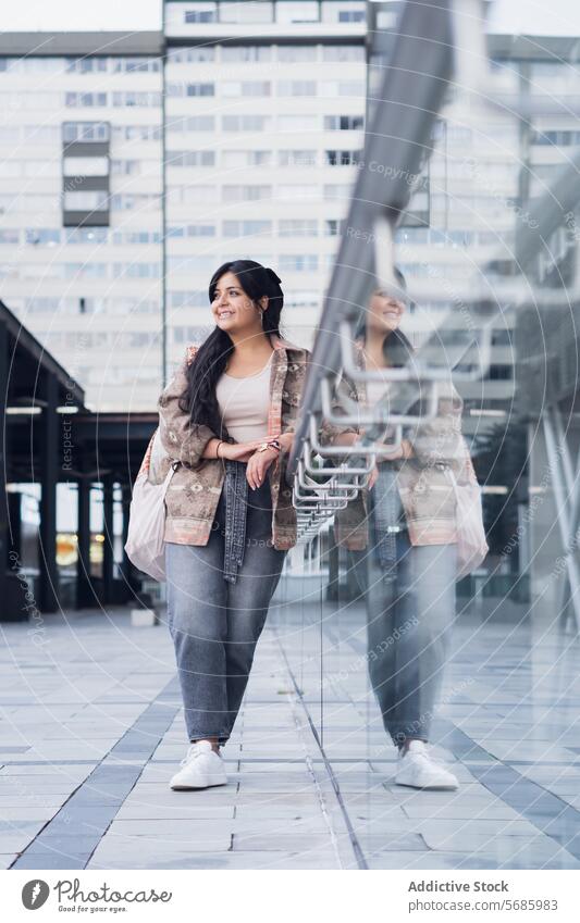 Stylish young woman standing in street style confident top curvy sneakers jeans smile building jacket modern urban outfit female city happy contemporary lady