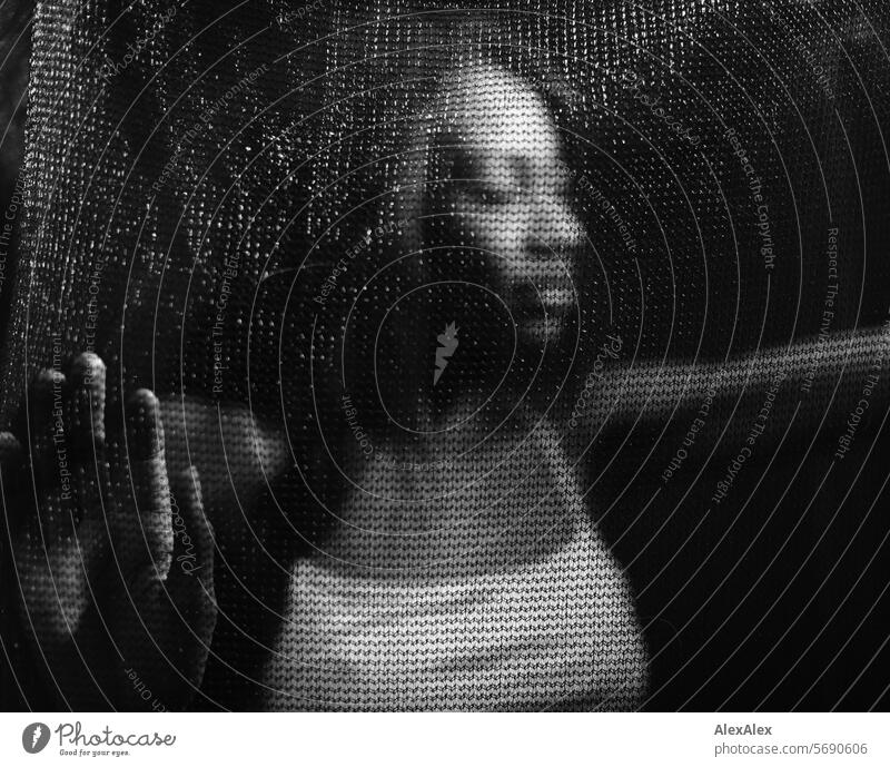 Young, long-haired woman supports herself behind a transparent curtain/net in the semi-darkness Woman Young woman Long-haired Dark Black black-and-white Net