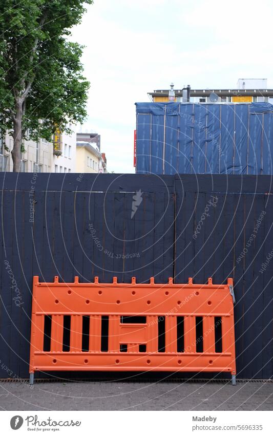 Plastic barrier in bright orange in front of dark construction fence at Neumarkt in the city center of Cologne on the Rhine structure Pattern line course
