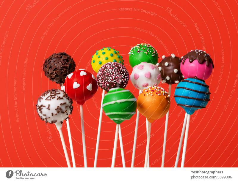Multicolored cake pops isolated on a red background assortment baking ball blue bright candy chocolate close up colorful colors confectionery dark delicious