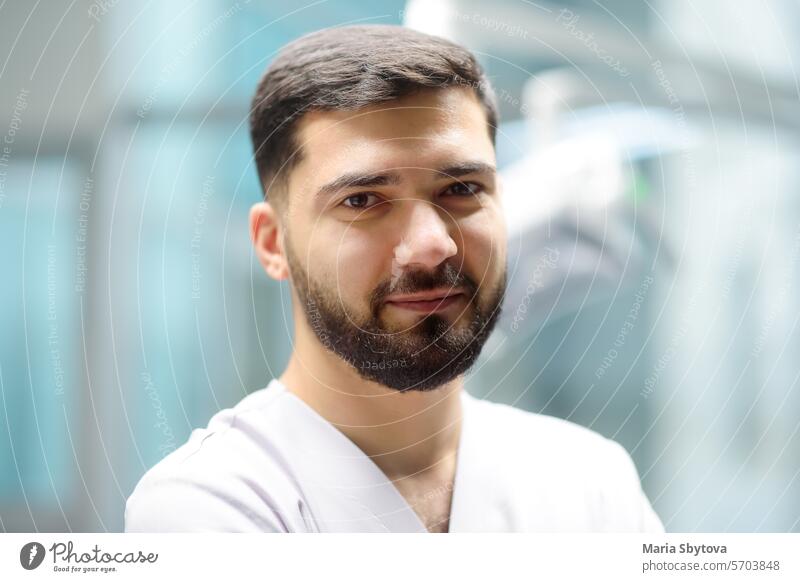 Portrait of a smiling dentist looking at camera in the office of a modern dental clinic. The doctor orthodontist is at work. portrait stomatology man handsome