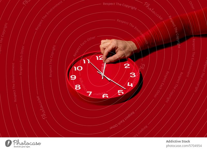 Adjusting time on a red wall clock hand minute hour background modern adjust match set concept deadline change time management punctuality speed countdown