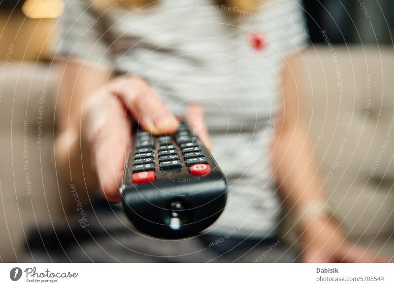 Woman holds TV remote control and switch channels watching TV television media tv clicker hand entertainment person device living room sofa holding fingers