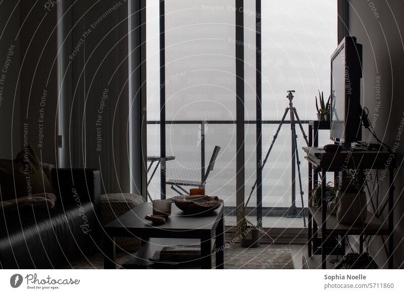 Dim living room with furniture looking out onto a foggy balcony with a tripod Room Living room livingroom living rooms living space home interior