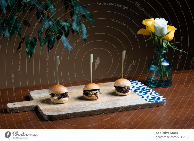 Mini beef burgers with cheddar cheese on wooden board mini rustic gourmet melted served vase yellow rose fresh skewer canapé appetizer snack elegant