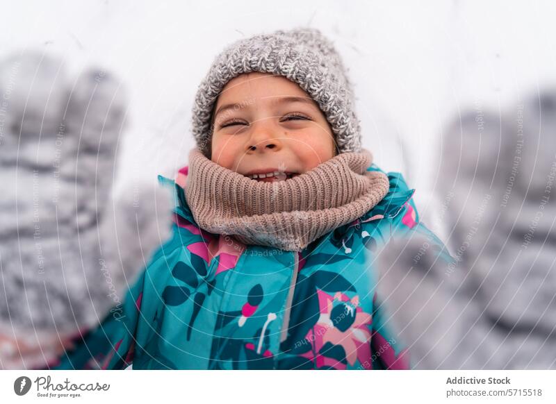 Happy child with mittened hands raised, smiling in a snowy winter setting Child smile happy outdoor joy scarf cold playful coat cheerful season fun knitwear