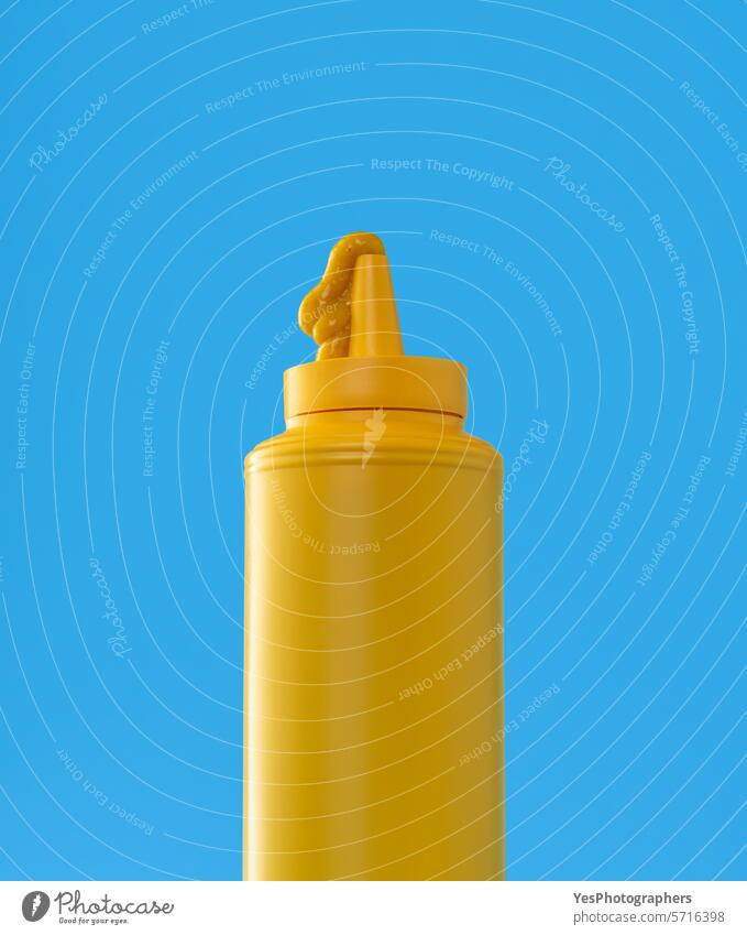 Mustard plastic bottle close up, minimalist on a blue background blank bright clean color condiment copy space creative cuisine cut out delicious design drip