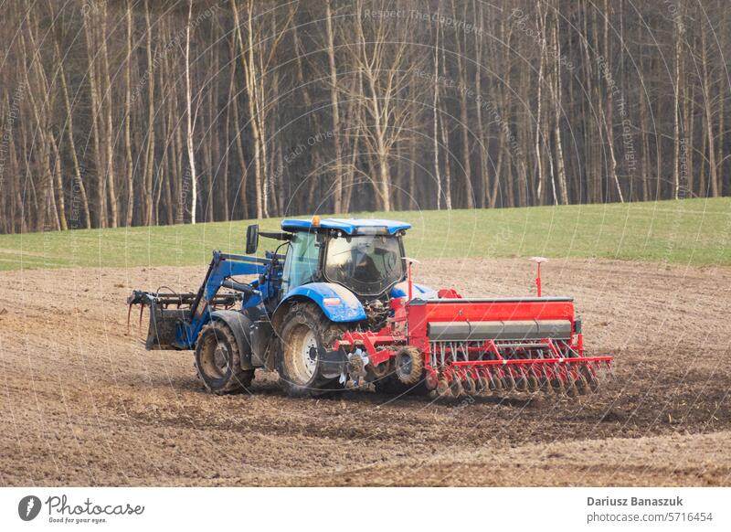 Agricultural tractor with seeder in the field, spring day agriculture land machinery agricultural sowing farm farmer industry farming work equipment countryside
