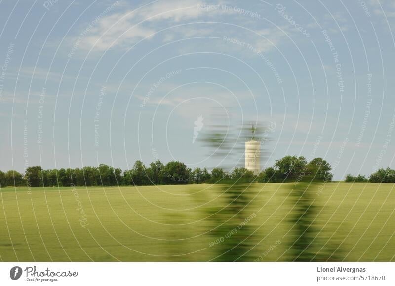 Blurred speed effect with green trees through a window over meadows and a white silo with blue sky and few clouds Field Meadow Speed effect blurriness Tree