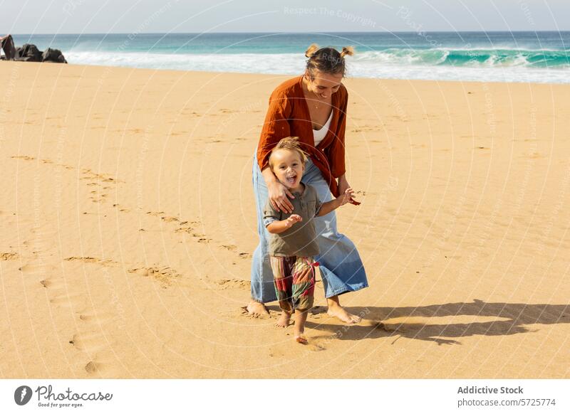 Joyful mother and child playing on sandy beach family fun ocean boy wave smile joy sunny childhood carefree parent seaside toddler bonding laughter quality time