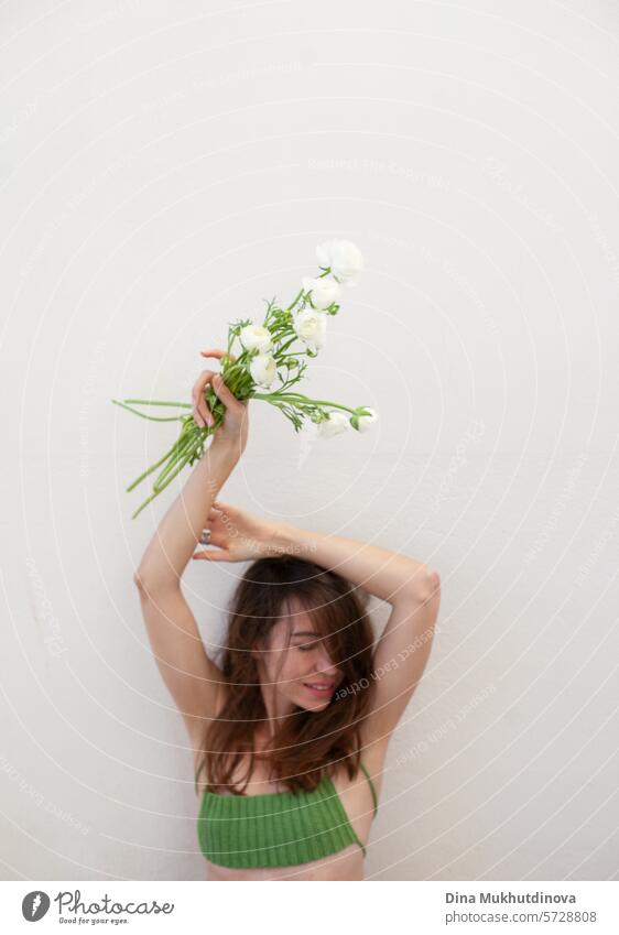 beautiful woman in green crochet handmade top with white ranunculus flowers bouquet on white wall minimal background Woman youthful Spring Green Crochet Top