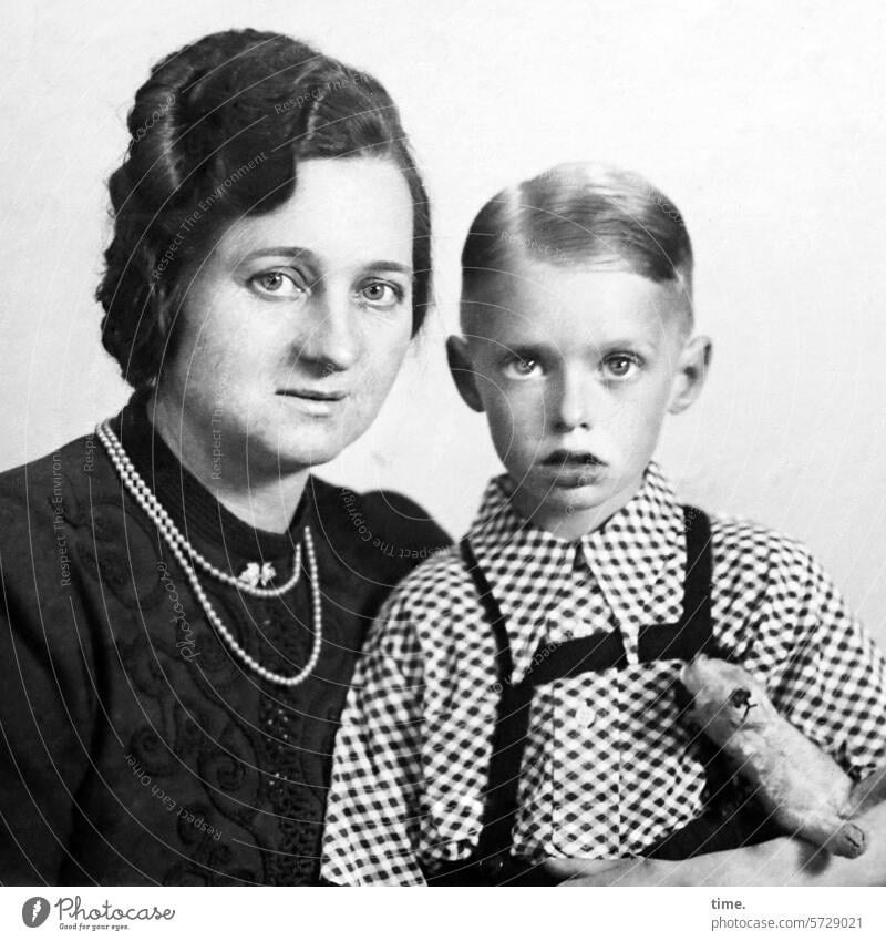 Mother with son and cuddly toy Woman Boy (child) portrait Dress Sit Hand Shirt Suspenders Anxious Looking into the camera Jewellery Dark-haired Blonde eyes