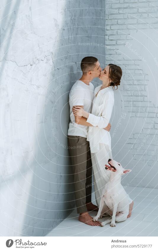 young couple guy and girl in a bright room playing with pet brick brown corner dog ears friend gray grey light man's friend nose pink smooth tail teeth three