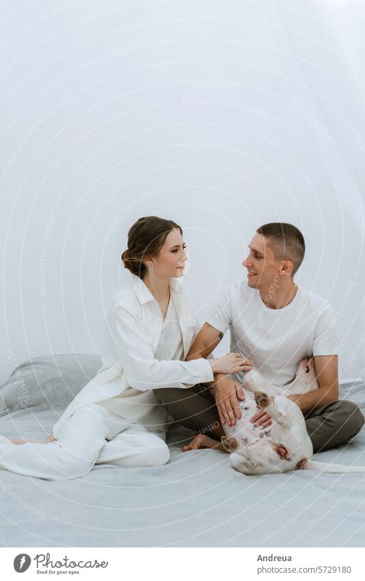 young couple guy and girl in a bright room playing with pet brick brown corner dog ears friend gray grey light man's friend nose pink smooth tail teeth three