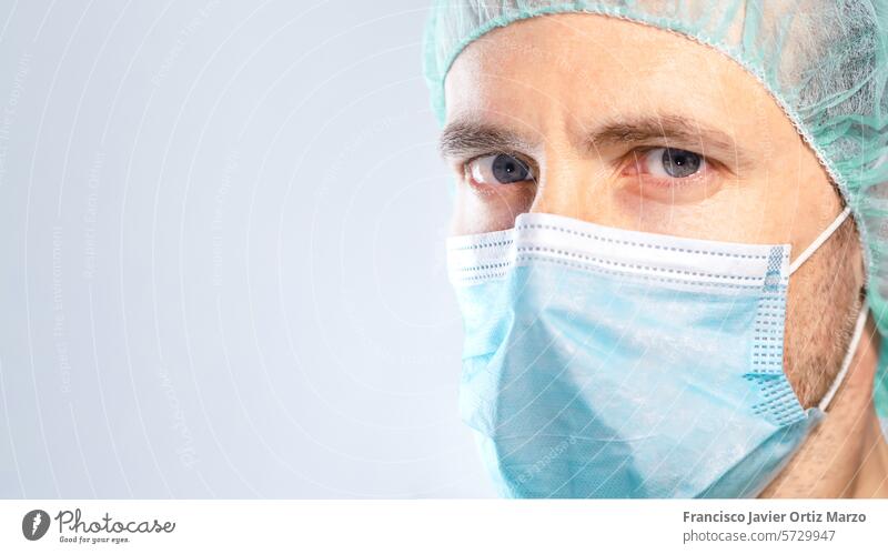 Close-up of doctor with blue eyes protected by mask and cap. Selective focus. medicine scientist man face mask care scientific caucasian protection chemistry