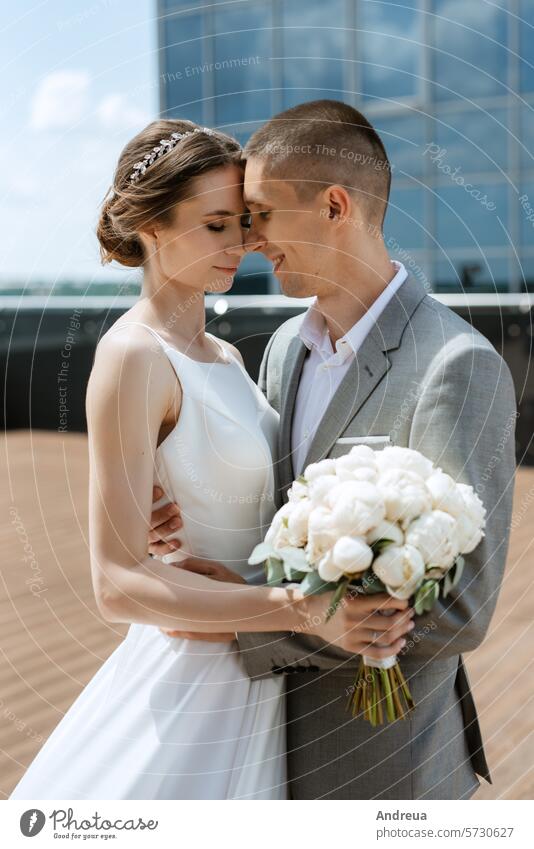 bride and groom first meeting on the roof of skyscraper blue bouquet city couple day dress forever happiness joy newlyweds smiles suit summer together top two