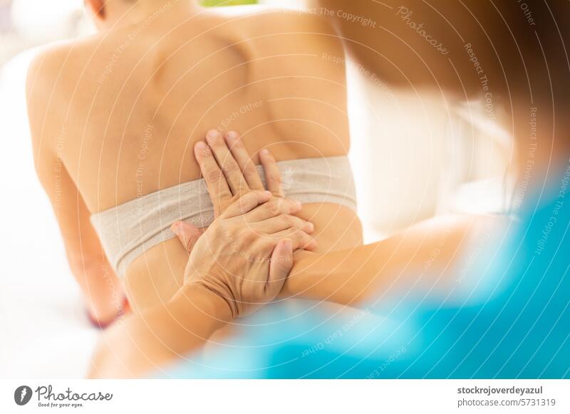 A physiotherapist puts pressure on her patient's back, using manual therapy clinic rehabilitation health care physiotherapy massage treatment body spa wellness