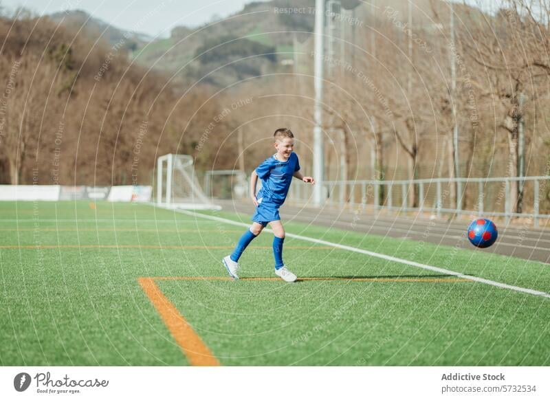 Young soccer player in action on a sunny day boy sport active ball game kid youth football outdoor athletic competition fitness fun grass green health healthy