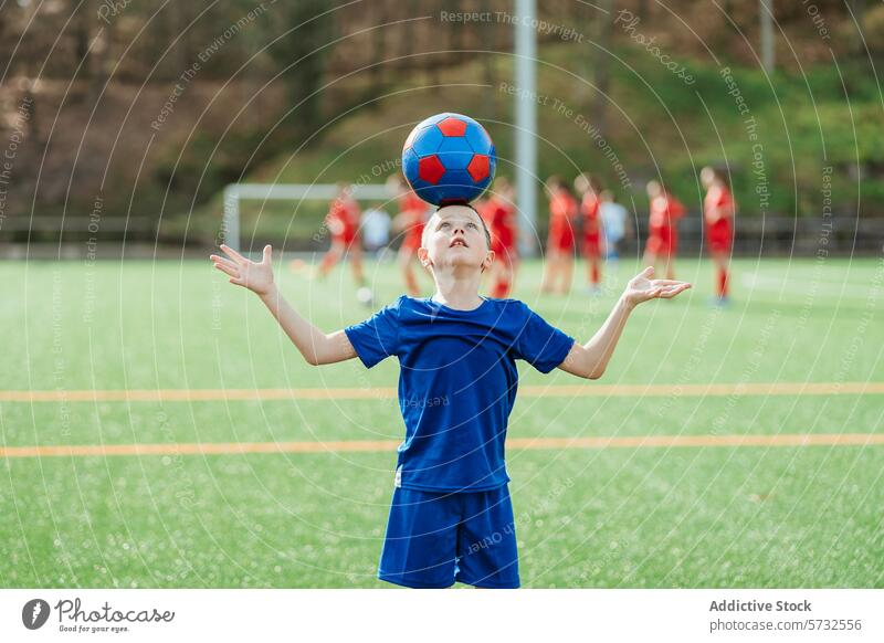 Young soccer player balancing ball on forehead young focus practice background sport youth training skill field outdoor summer child boy blue uniform recreation