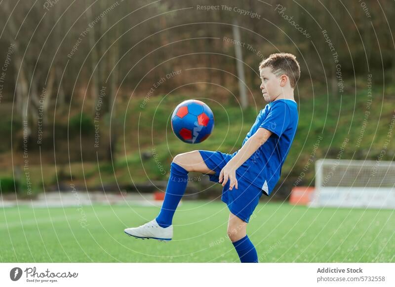 Young soccer player skillfully controlling the ball boy young sport practice outdoor field uniform blue youth focus concentrated football kid athletic active