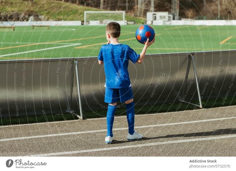 Young player preparing for soccer match boy football kid sideline sport young field blue uniform holding ready game anticipation athlete outdoor stadium