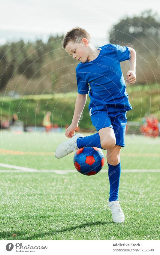 Young soccer player controlling the ball on field boy sport game outdoor young child sportswear blue youth skill football athlete grass team action active