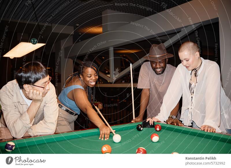 Diverse group of young people playing billiards game together in nightclub and having fun, shot with flash Black woman friend snooker pool diversity multiethnic