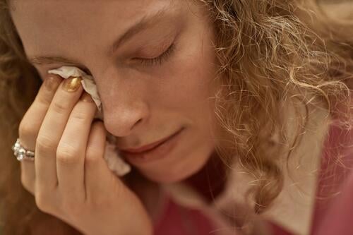 Close up of young woman crying during emotional therapy session and wiping tears with tissue, copy space girl support group mental health meeting hold grief