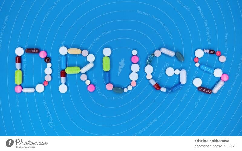 Multicolored capsules in word drugs. Blue background. Pharmacy, antidepressants, medicine concept. medication pharmaceutical medical health antibiotic pharmacy