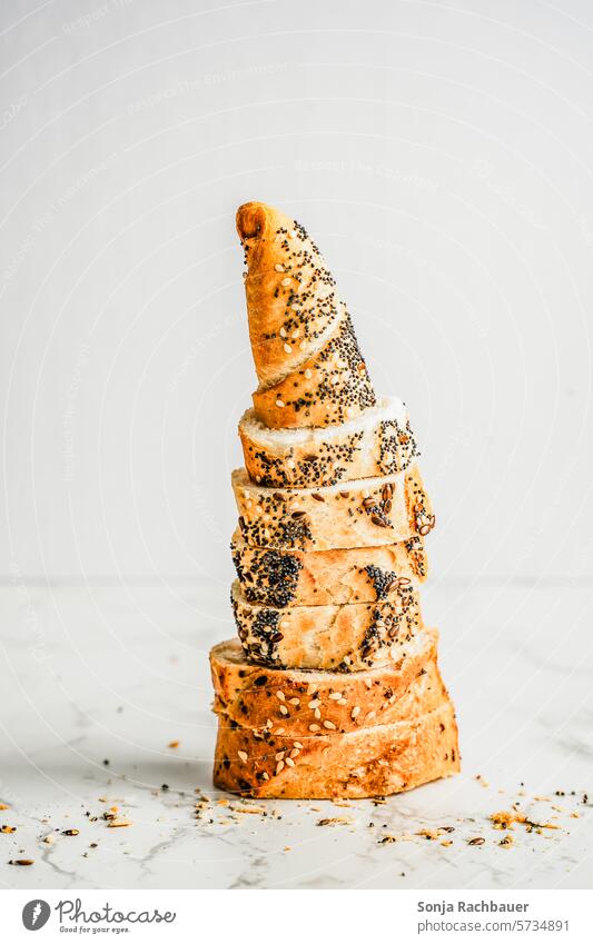 Slices of baguette stacked on a white table. Baguette baked Crisp Food Bread Crust Tradition Flour Poppy White Brown Food photograph Neutral Background