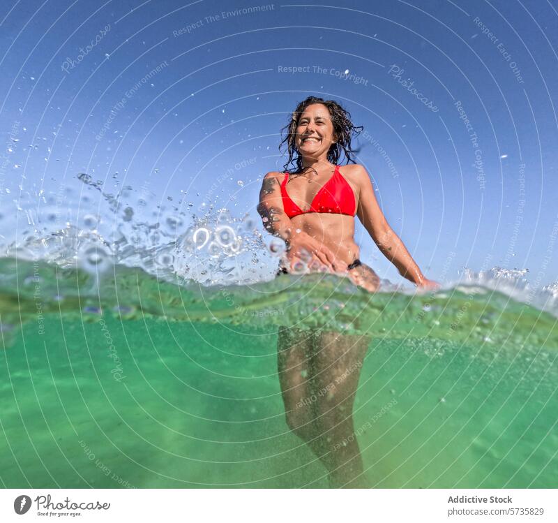 Woman enjoying a refreshing swim in clear blue water woman summer submerged sparkling sun rays bikini red smile happy leisure activity ocean sea holiday