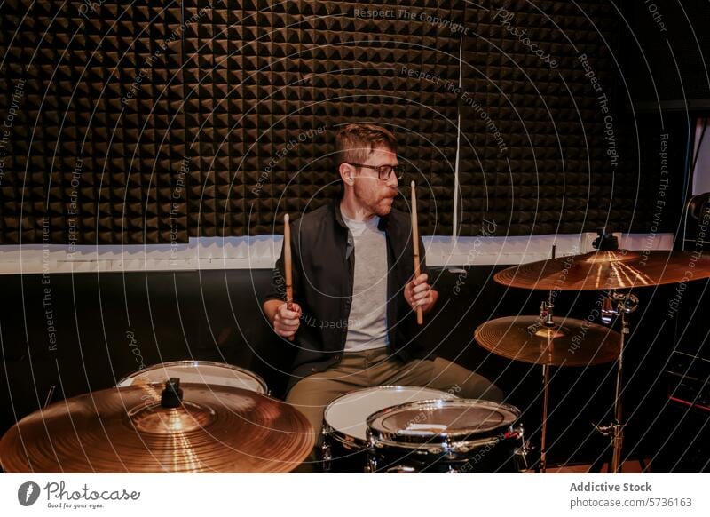 Drummer performing in studio with full drum set musician drummer cymbals male man performance playing rehearsal band sticks glasses looking away entertainment