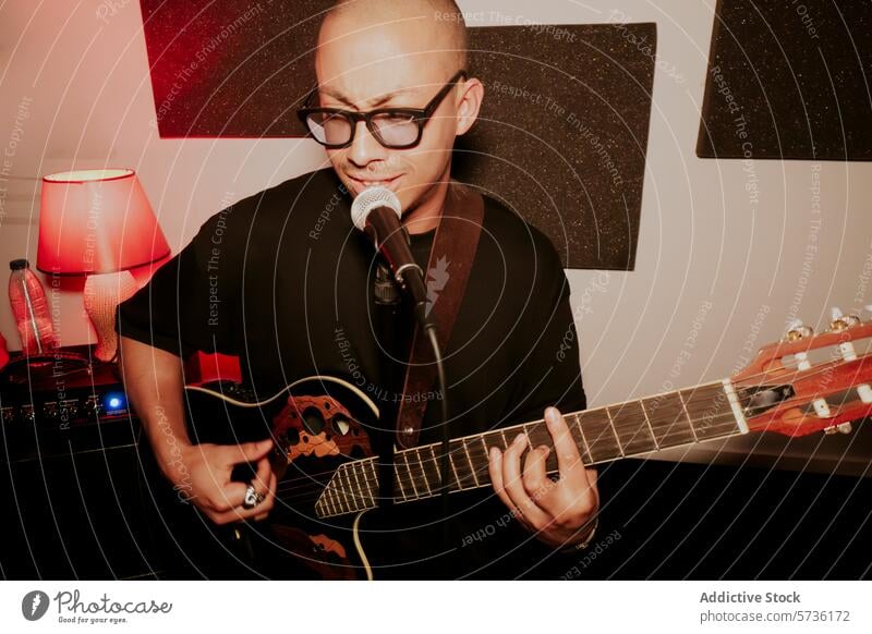 Male guitarist performing with microphone in cozy setting music acoustic guitar singing performance male musician intimate room lamp glasses indoor