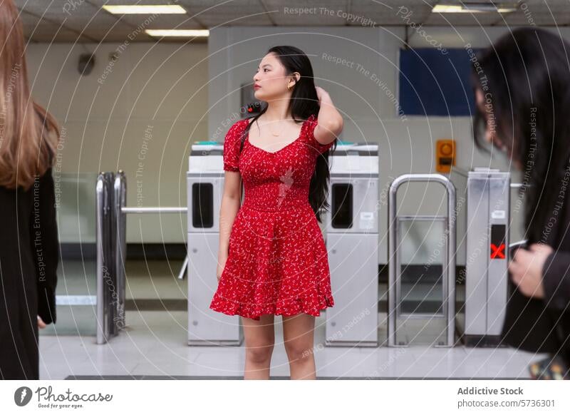 Young woman in red dress waiting at transit station asian stand vibrant urban casual patience young body language turnstile entrance gate indoor commute