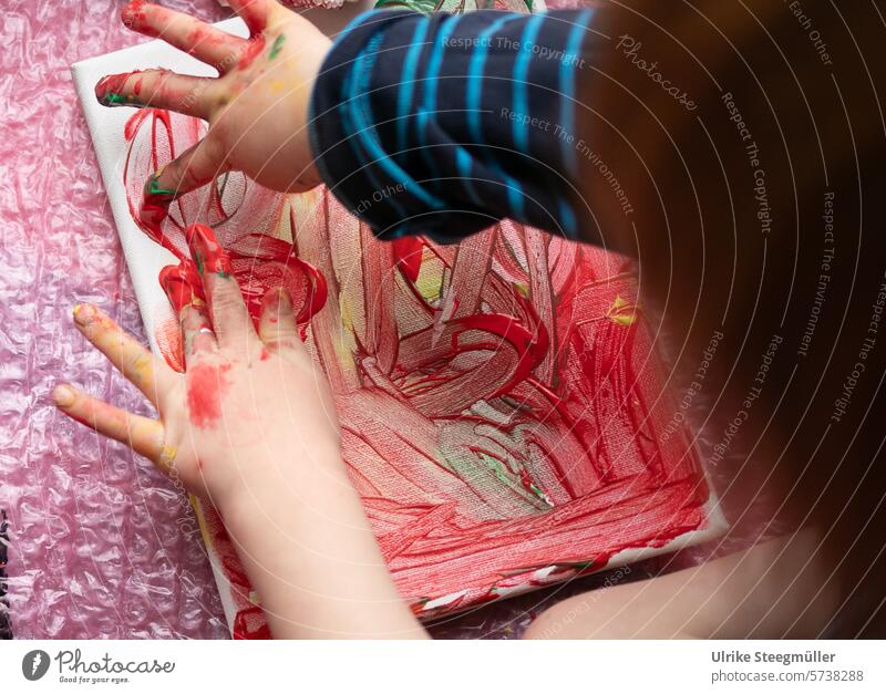A child paints with his hands on a canvas children's art Painting with fingers Life with children Red Yellow variegated Hand Fingers Joy fun Window painting