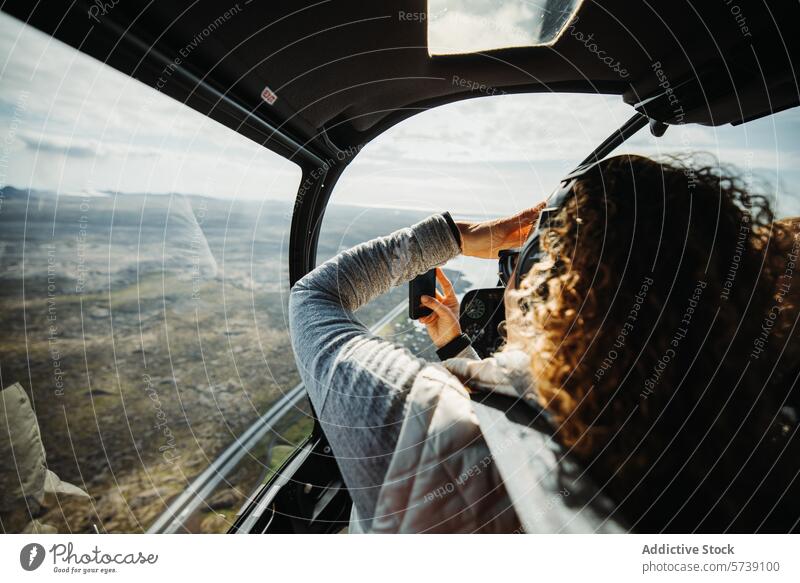 Woman taking photo on smartphone while on a helicopter Sightseeing in Iceland's Wild Terrain iceland tour sightseeing woman landscape rugged aerial view