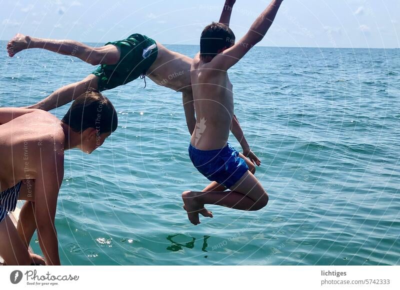 Jumping chance - Three boys joyfully jump wildly straight into the sea Guys Summer Water Ocean warm Sun cooling Headfirst dive Joy