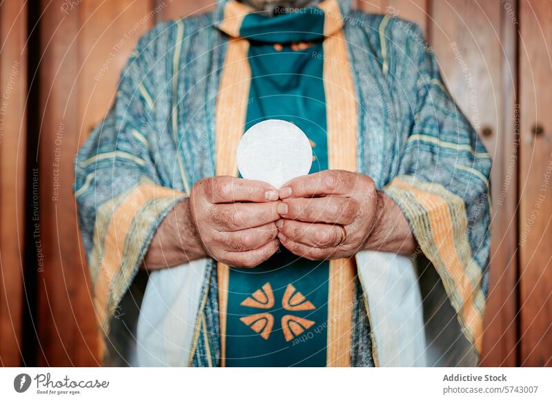 Close-up of anonymous priest's hands presenting the Eucharistic host, a sacred symbol in the Christian Holy Communion communion sacrament holy ceremony