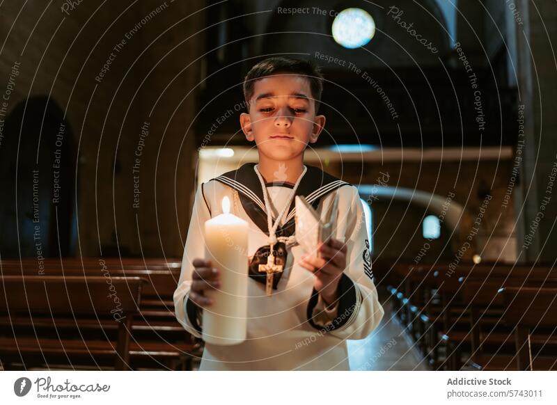 A solemn young boy, dressed in traditional First Communion garb, holds a lit candle and cross in a serene church setting first communion attire religious