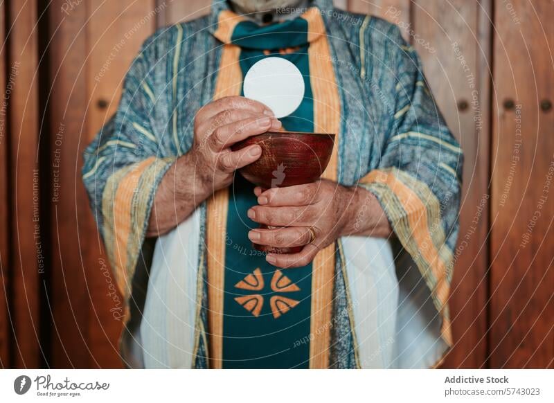Anonymous priest elevates the Eucharistic host above a chalice, a central ritual in the celebration of the Christian Communion service communion sacrament mass