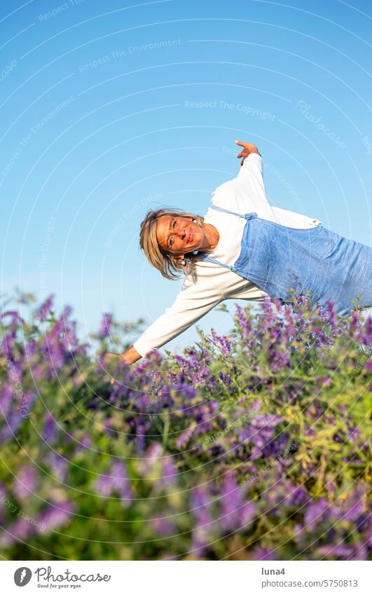 Cheerful young woman rejoices in a meadow of flowers Woman Laughter jubilate cheerful Young woman Brash high-spirited outstretched arms Meadow fortunate