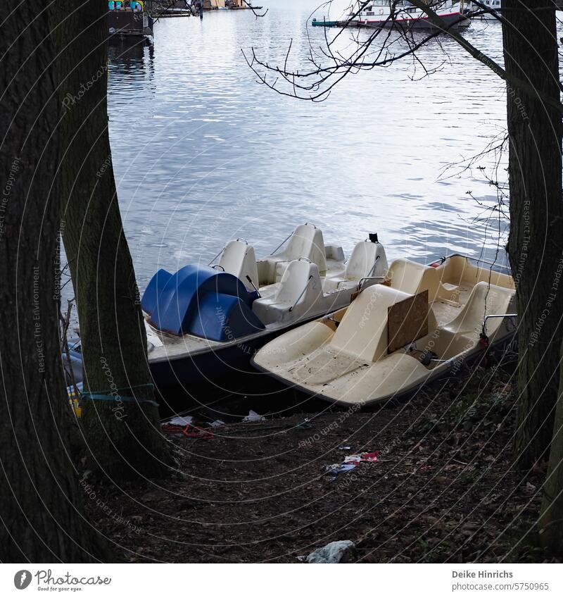 Two pedal boats are waiting to be used on the banks of the Spree after the cold season. Berlin Rummelsburg Water Tretbot free time pleasure Aquatics