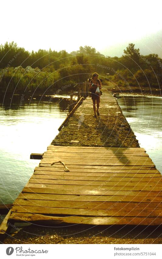 Woman walking on a wooden walkway Hiking River Exotic Footbridge Bridge muggy evening mood Summer voyage globetrotter vacation make a pilgrimage Pilgrim