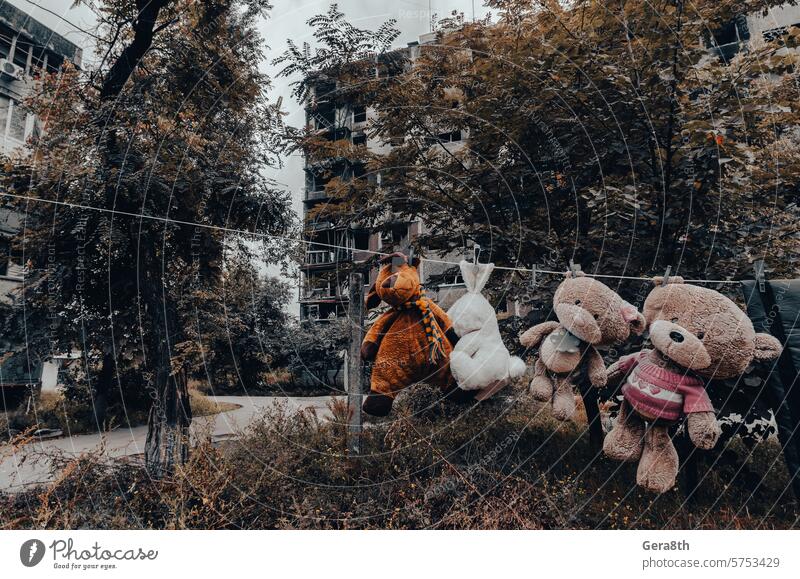 children's toys hang on a rope against the background of destroyed burnt houses in Ukraine Donetsk Kherson Kyiv Lugansk Mariupol Russia Zaporozhye abandon