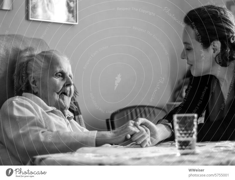 The granddaughter holds the old woman's hand tenderly and talks to her in a friendly manner senior citizens demented dementia age Old Woman visit Family