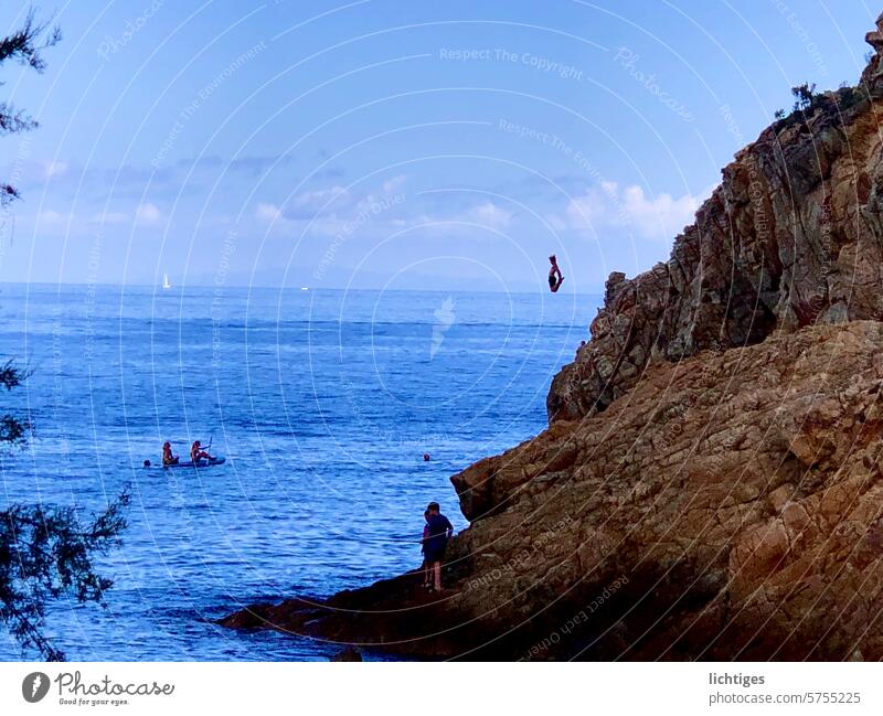 Jumping dot - boy jumps from a great height from a rock into the sea Rock Ocean Stunt Brave cliff jump Cliff daredevil