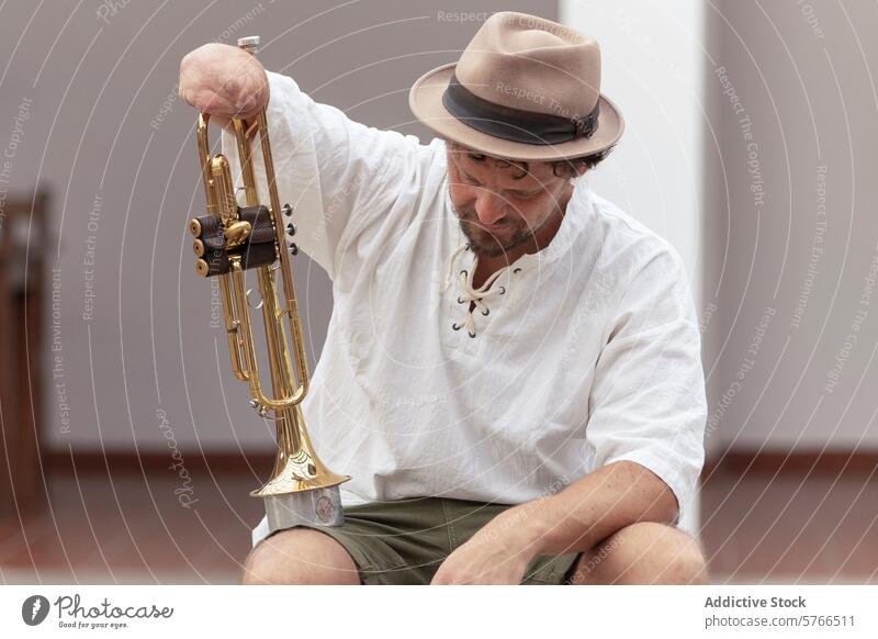 Inspiring one-armed trumpeter practicing his craft musician practice home determination adaptability hat casual sitting perseverance instrument passion hobby